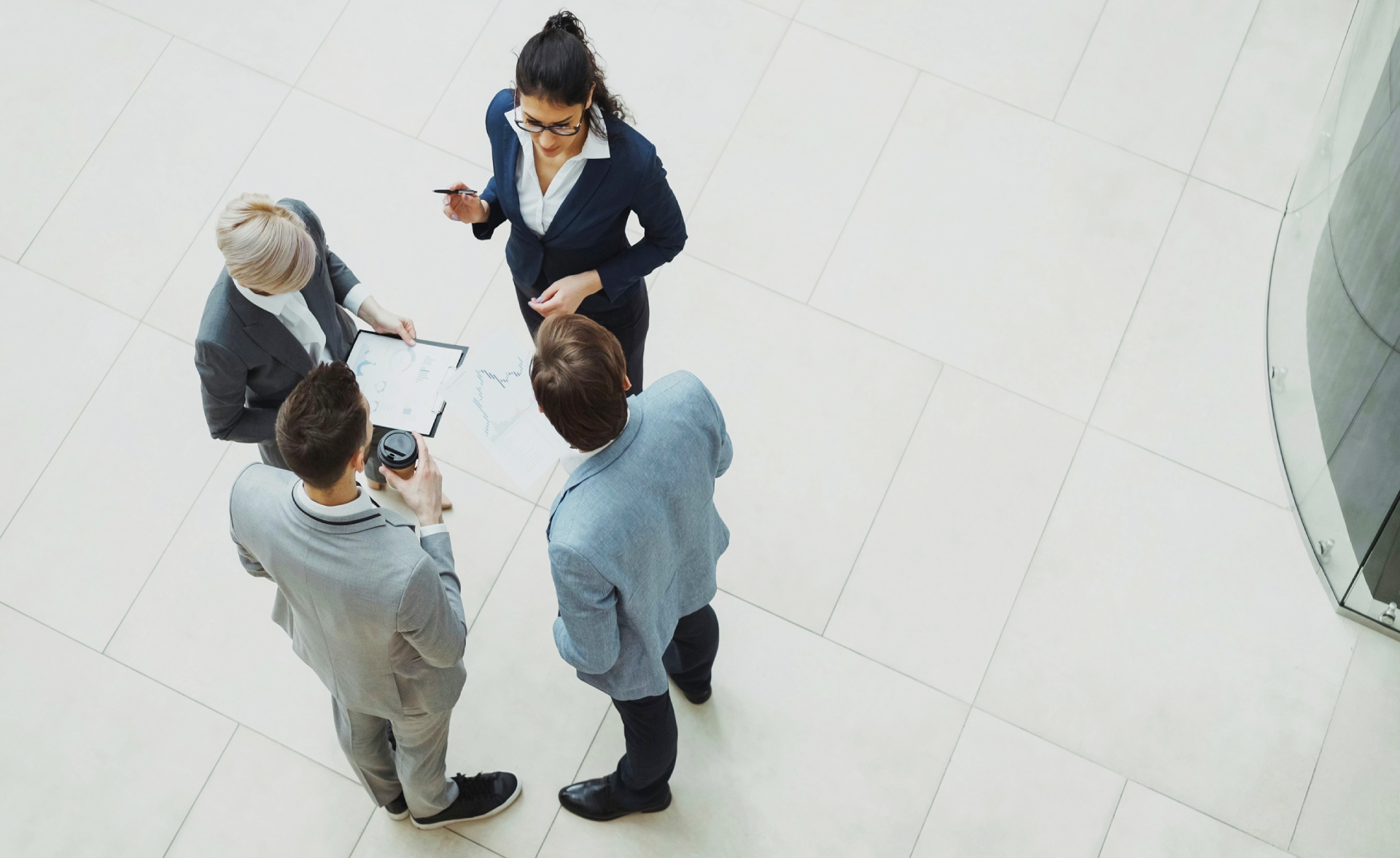 Overhead view of four colleagues reviewing a chart in an office lobby