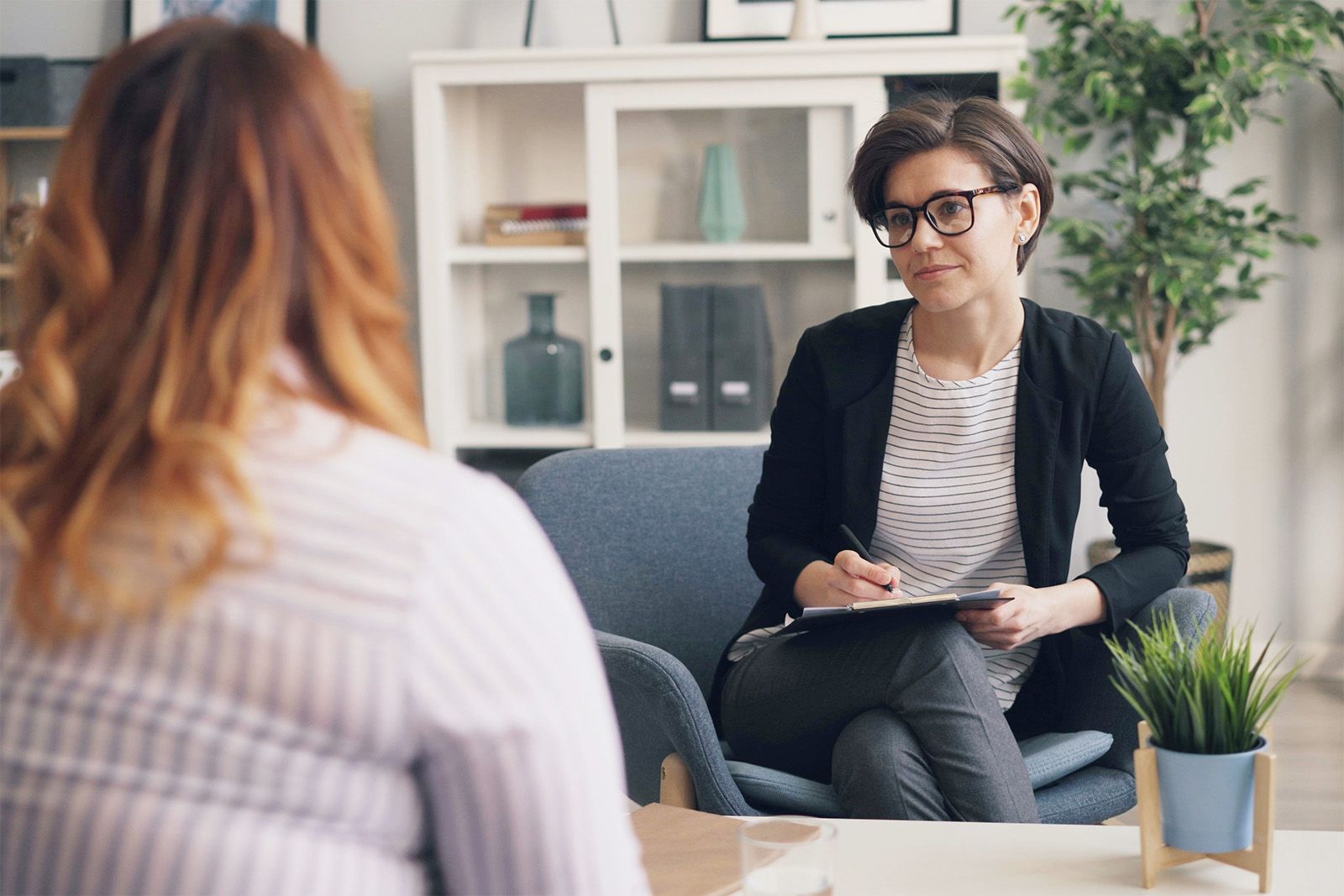 Interviewer with a clipboard listening to a candidate across a desk
