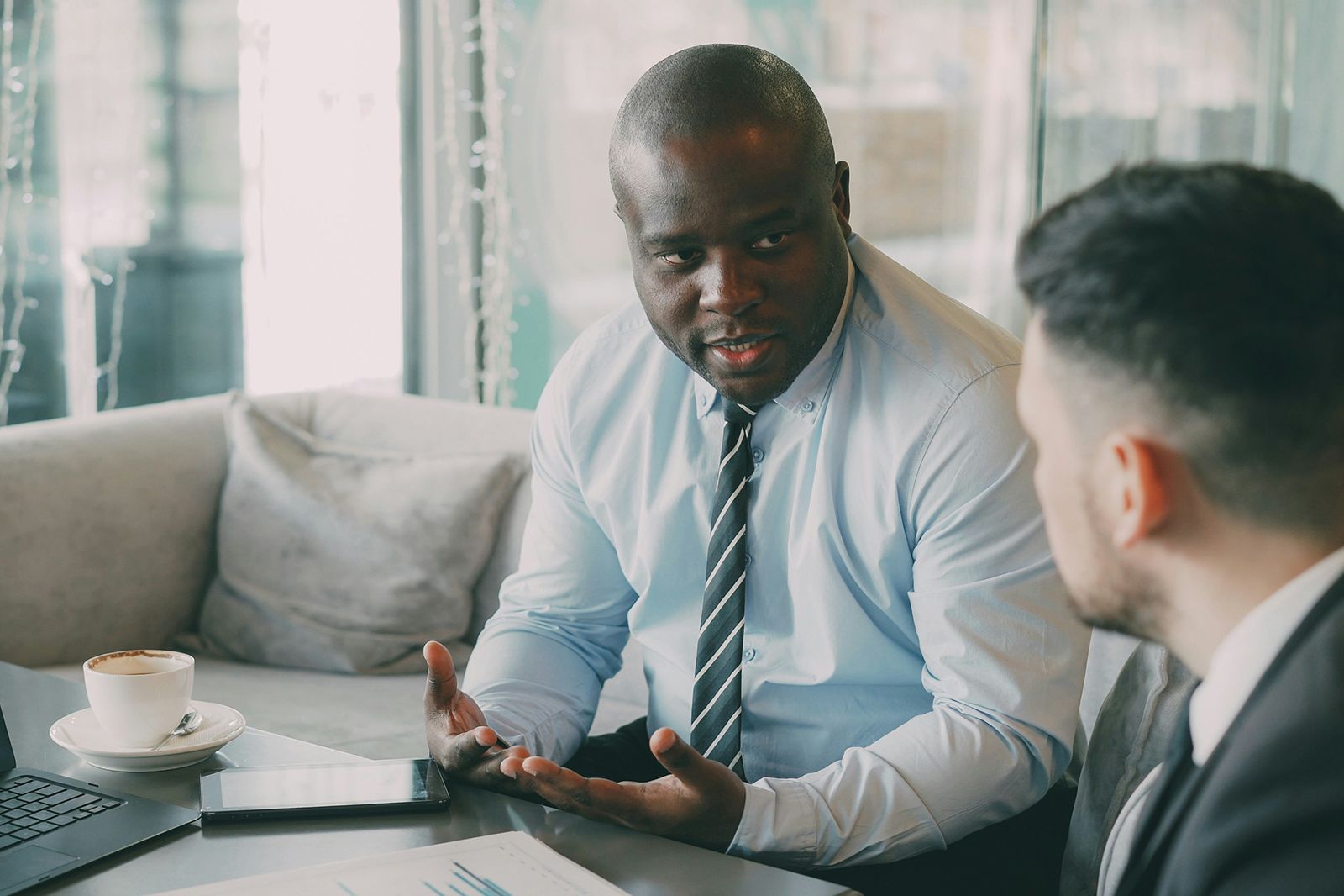 Manager in a shirt and tie explaining a plan to a colleague over coffee